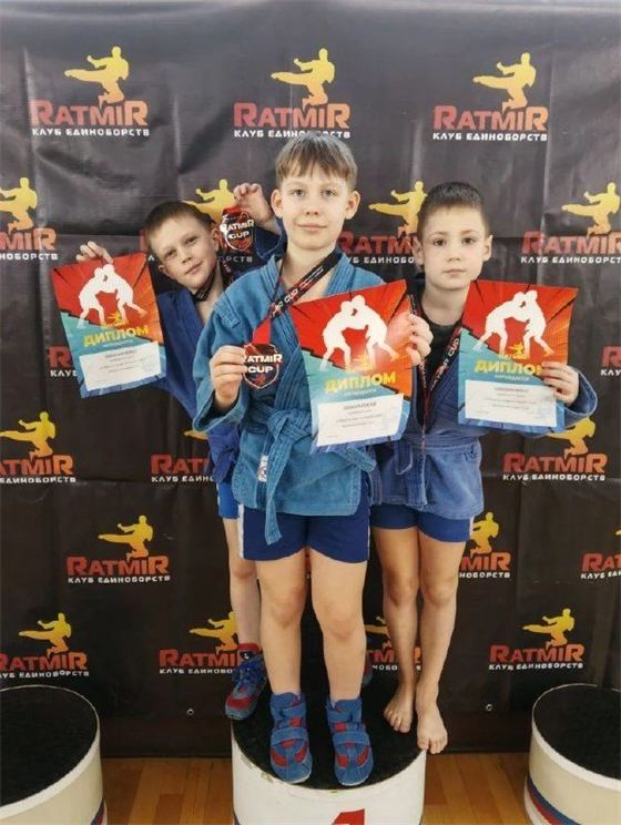 Три мальчика в синих самбовках с дипломами Ratmir Cup на пьедестале