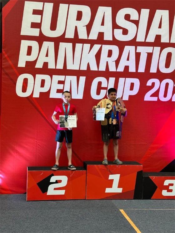 Пьедестал Eurasian Pankration Open Cup: два мальчика, один с чемпионским поясом