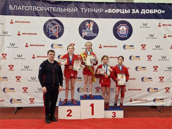 Пьедестал благотворительного турнира «Борцы за добро»: четыре девочки в красных самбовках с грамотами и медалями